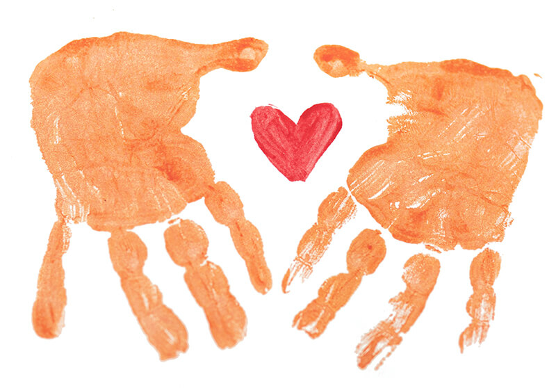 Zwei Handabdrücke in Orange liegen sich gegenüber - Daumen an Daumen - und in der Mitte befindet sich ein rotes gemaltes Herz.